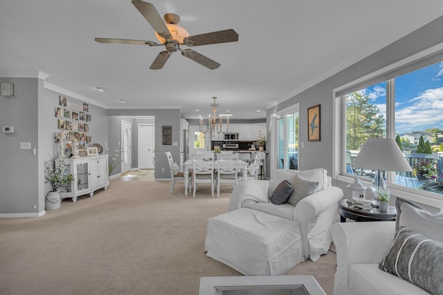living room featuring crown molding, ceiling fan with notable chandelier, light colored carpet, and baseboards