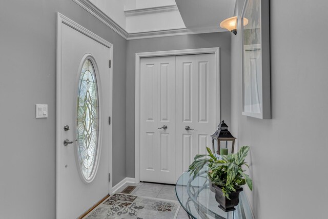 entryway with crown molding, light tile patterned floors, and baseboards