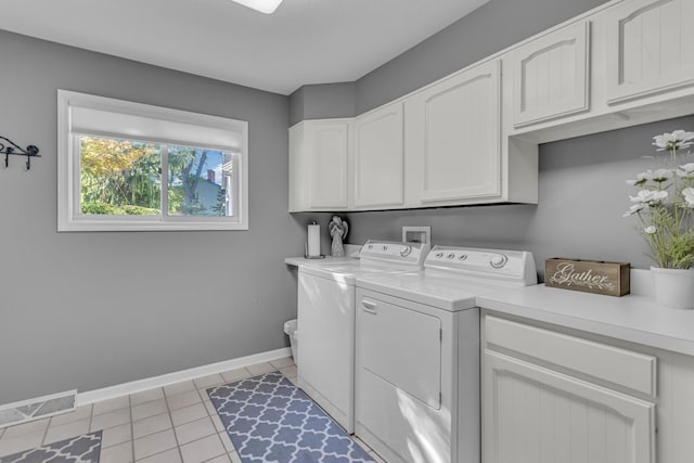 laundry room featuring light tile patterned floors, separate washer and dryer, visible vents, baseboards, and cabinet space