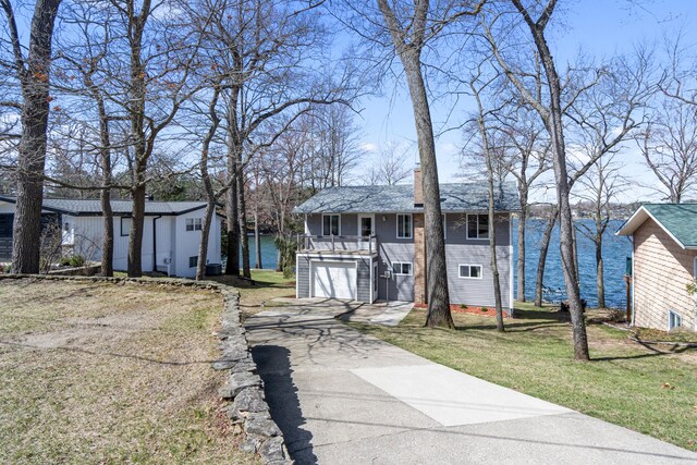 11672 Bradley Dr, Jerome, MI 49249 - view of front of house with a residential view, a garage, aphalt driveway, a front yard, and a water view