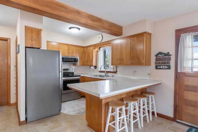 11672 Bradley Dr, Jerome, MI 49249 - kitchen with a peninsula, light countertops, a sink, stainless steel appliances, and brown cabinets