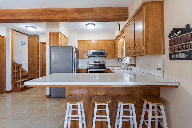 11672 Bradley Dr, Jerome, MI 49249 - kitchen featuring a sink, light countertops, a peninsula, brown cabinets, and stainless steel appliances