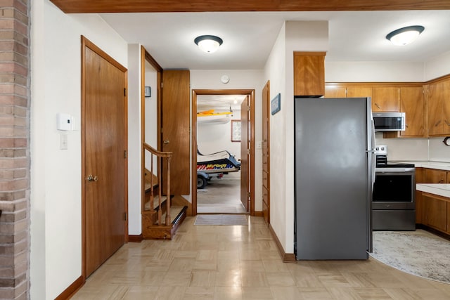 11672 Bradley Dr, Jerome, MI 49249 - kitchen with light countertops, baseboards, brown cabinetry, and appliances with stainless steel finishes