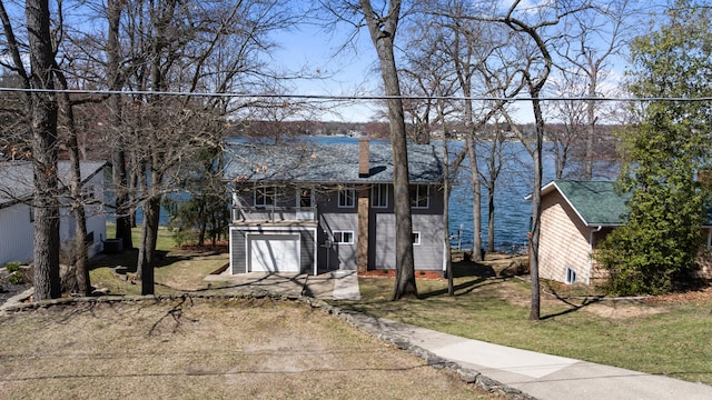 11672 Bradley Dr, Jerome, MI 49249 - view of front of house featuring a garage, a front yard, driveway, and a water view