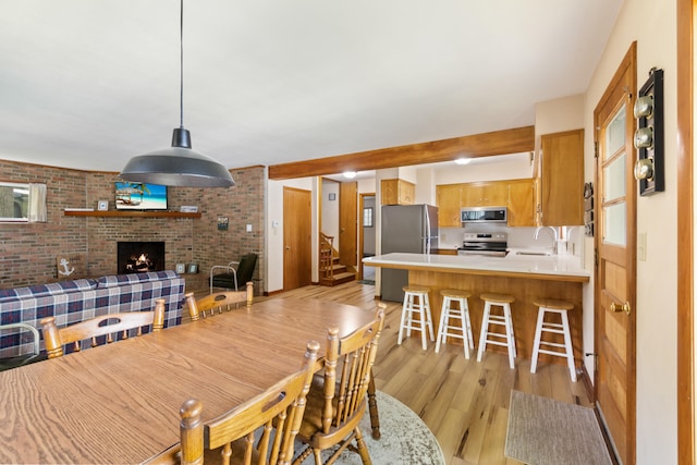 11672 Bradley Dr, Jerome, MI 49249 - dining space featuring light wood-style flooring, a fireplace, and stairs