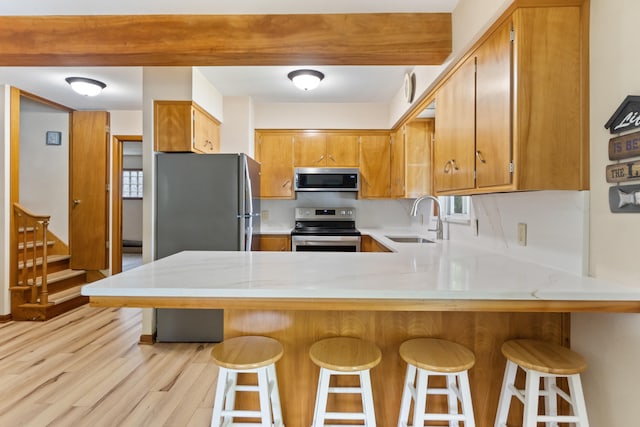 11672 Bradley Dr, Jerome, MI 49249 - kitchen with appliances with stainless steel finishes, light countertops, light wood-style floors, a peninsula, and brown cabinetry