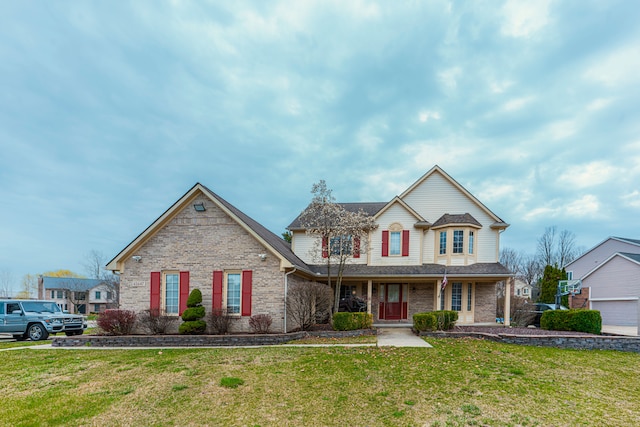 traditional home with brick siding, a front yard, covered porch, and roof with shingles