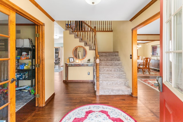 foyer entrance with stairway, crown molding, baseboards, and wood finished floors