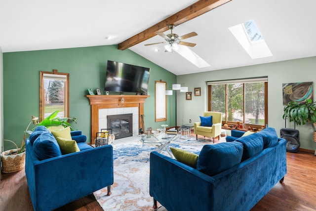 living room with lofted ceiling with skylight, wood finished floors, a fireplace, and a ceiling fan