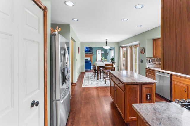 kitchen with recessed lighting, stainless steel appliances, decorative light fixtures, brown cabinetry, and dark wood-style flooring