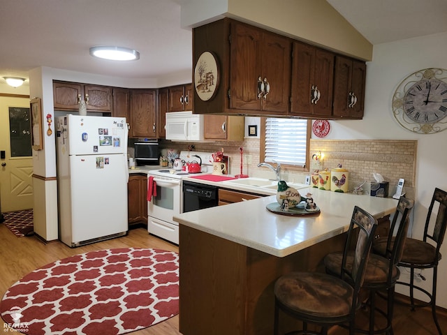 kitchen with light wood-style floors, white appliances, a peninsula, light countertops, and decorative backsplash