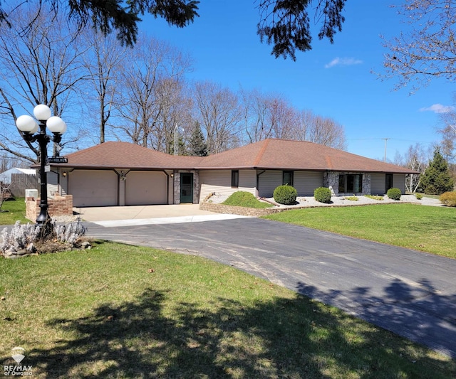 view of front facade featuring a front yard, a shingled roof, driveway, and an attached garage