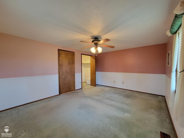 unfurnished bedroom featuring visible vents, ceiling fan, light colored carpet, and a textured ceiling
