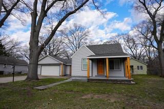 bungalow-style home with a front yard, a porch, and an outbuilding