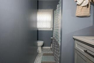 bathroom featuring toilet, vanity, baseboards, and a shower with curtain
