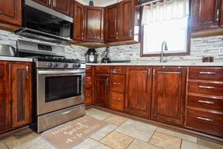kitchen with appliances with stainless steel finishes, a sink, light countertops, and backsplash