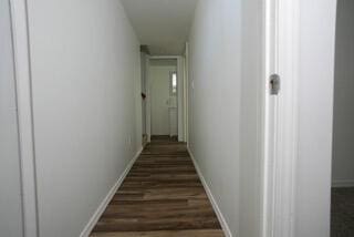 hall featuring dark wood-style floors and baseboards