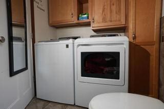 laundry room with light tile patterned floors, separate washer and dryer, and laundry area