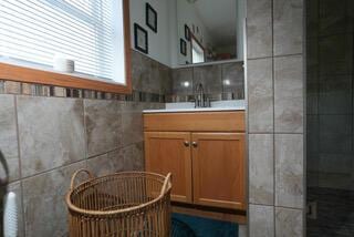 bathroom featuring a tile shower, tile walls, and vanity