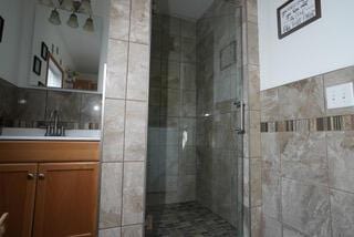 bathroom with vanity, tile walls, and a stall shower