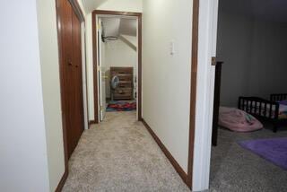 hall featuring baseboards and light carpet