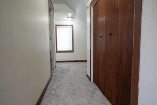 hall with light colored carpet and baseboards