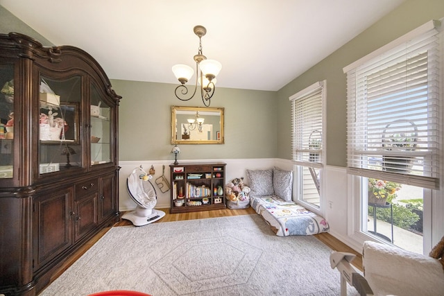 living area with wainscoting, an inviting chandelier, and wood finished floors