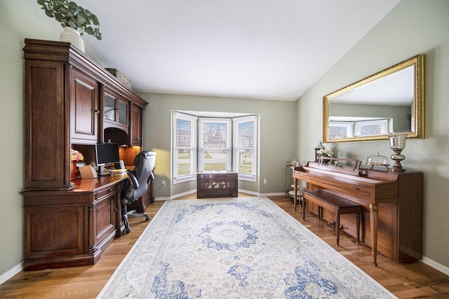 home office with light wood finished floors, baseboards, and lofted ceiling