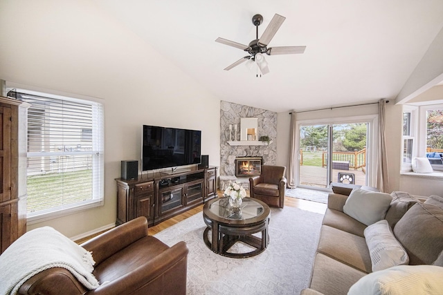 living area featuring ceiling fan, high vaulted ceiling, light wood-style floors, and a fireplace