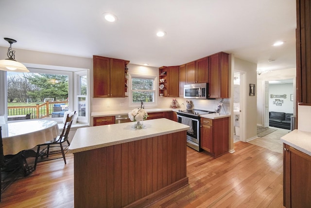 kitchen featuring light wood finished floors, light countertops, backsplash, and appliances with stainless steel finishes