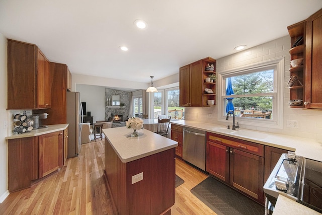 kitchen featuring tasteful backsplash, open shelves, a sink, light wood-style floors, and stainless steel appliances