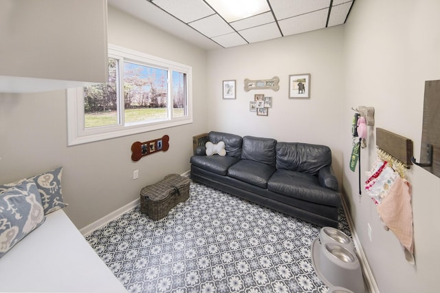 living room featuring a paneled ceiling, carpet flooring, and baseboards
