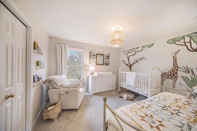 carpeted bedroom featuring a nursery area, a closet, and baseboards