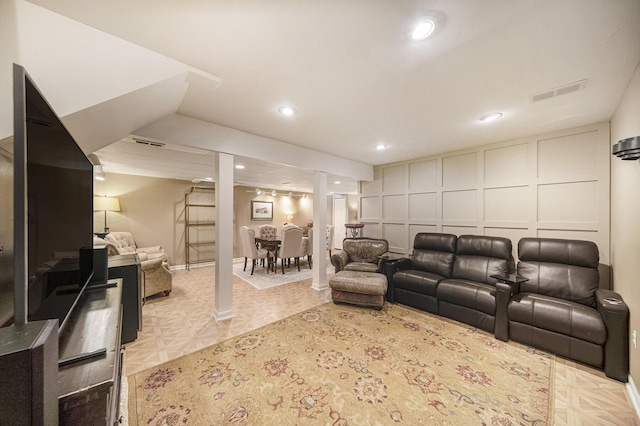 living area featuring a decorative wall, visible vents, and recessed lighting