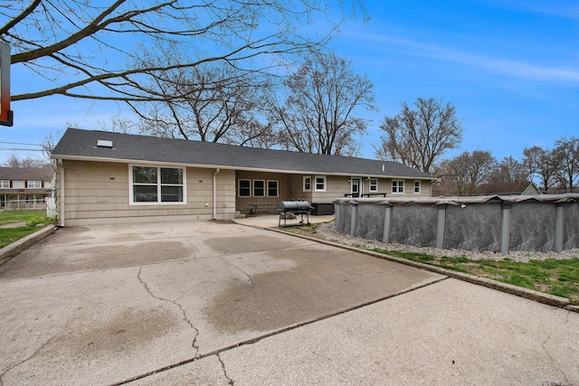 rear view of property featuring a patio and a covered pool