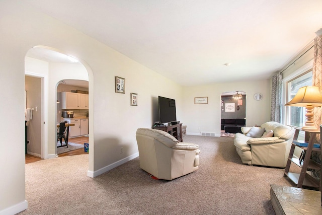 living area featuring visible vents, baseboards, arched walkways, and carpet