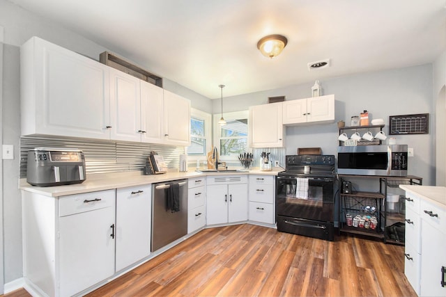 kitchen featuring light countertops, white cabinetry, stainless steel appliances, light wood finished floors, and a sink