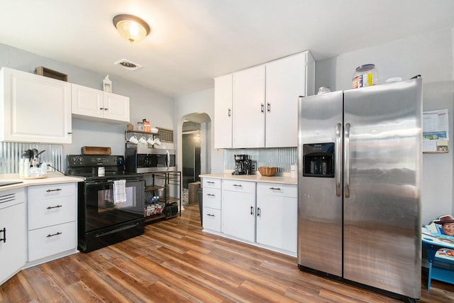 kitchen with arched walkways, wood finished floors, visible vents, and stainless steel appliances