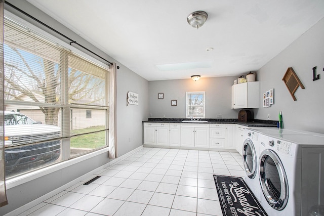 clothes washing area with visible vents, a skylight, light tile patterned flooring, washer and dryer, and cabinet space