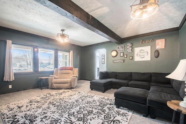 living room with a textured ceiling, carpet flooring, beamed ceiling, and arched walkways