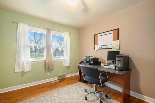 office featuring ceiling fan, visible vents, baseboards, and wood finished floors