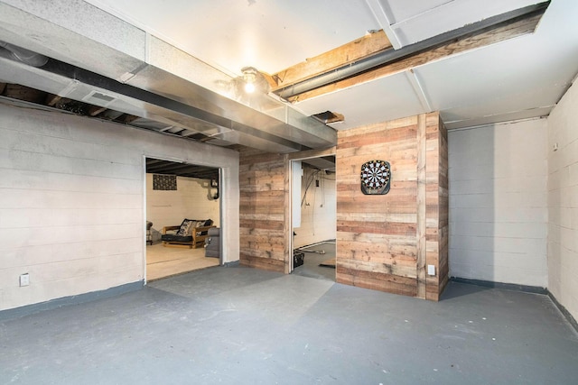 unfinished basement featuring wood walls and concrete block wall