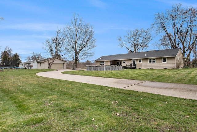 exterior space with a detached garage, a trampoline, a covered pool, a lawn, and an outbuilding