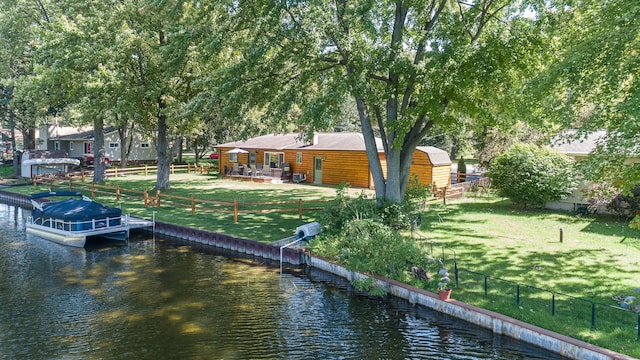 view of dock with a lawn, a water view, and fence