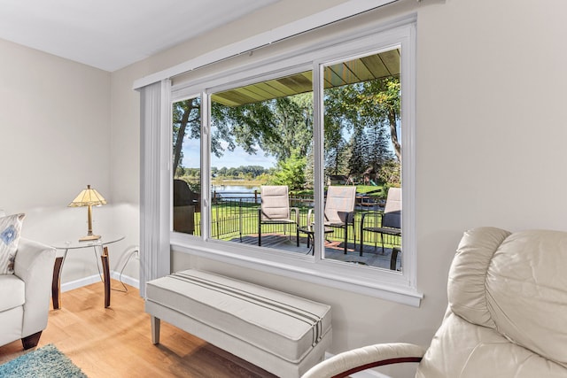 living area with a water view, baseboards, and wood finished floors