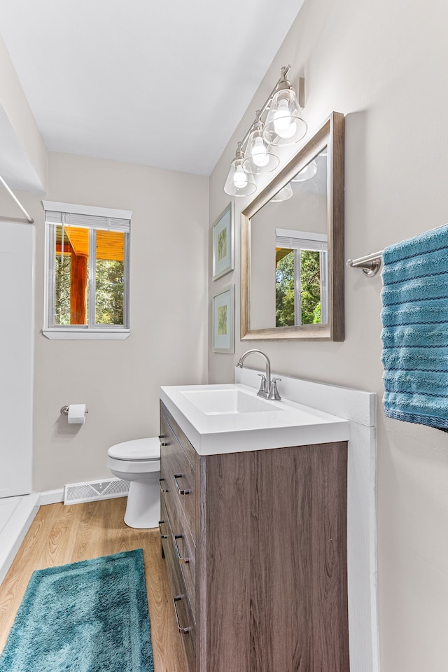 bathroom featuring vanity, toilet, baseboards, wood finished floors, and visible vents