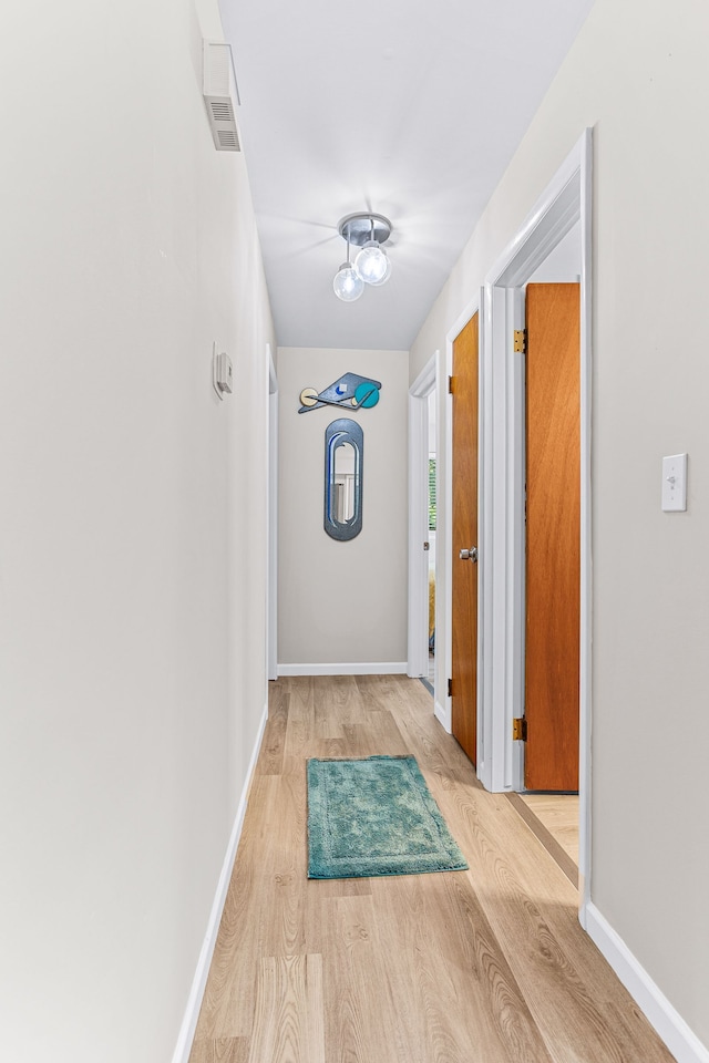 corridor with baseboards and wood finished floors