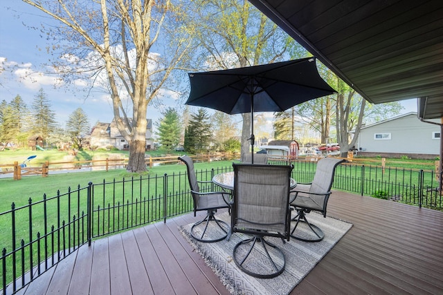 wooden deck with a lawn, fence, and outdoor dining space