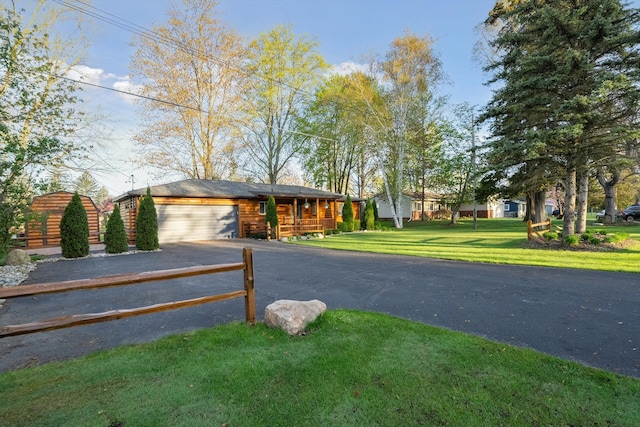 view of front of property featuring a garage, a front lawn, and aphalt driveway