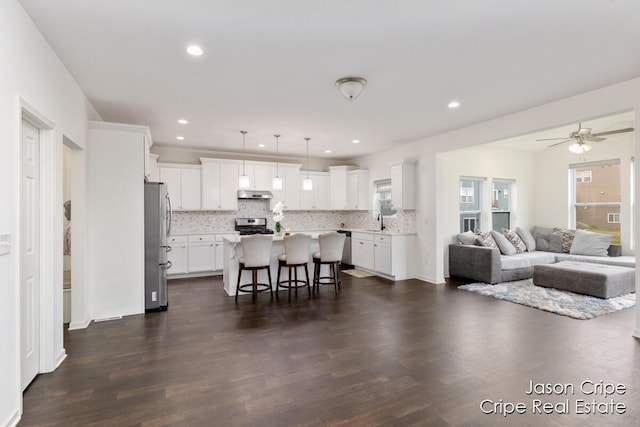 living room featuring dark wood-type flooring, a ceiling fan, and recessed lighting